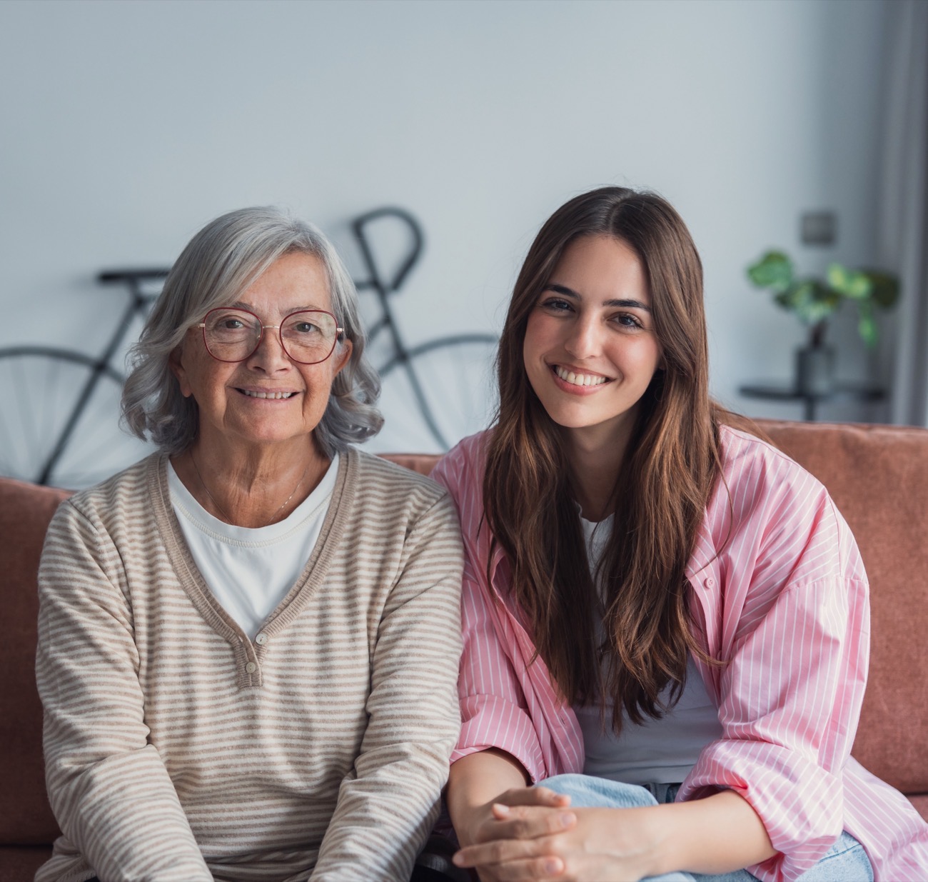 An older woman sitting with her caregiver on the sofa at home