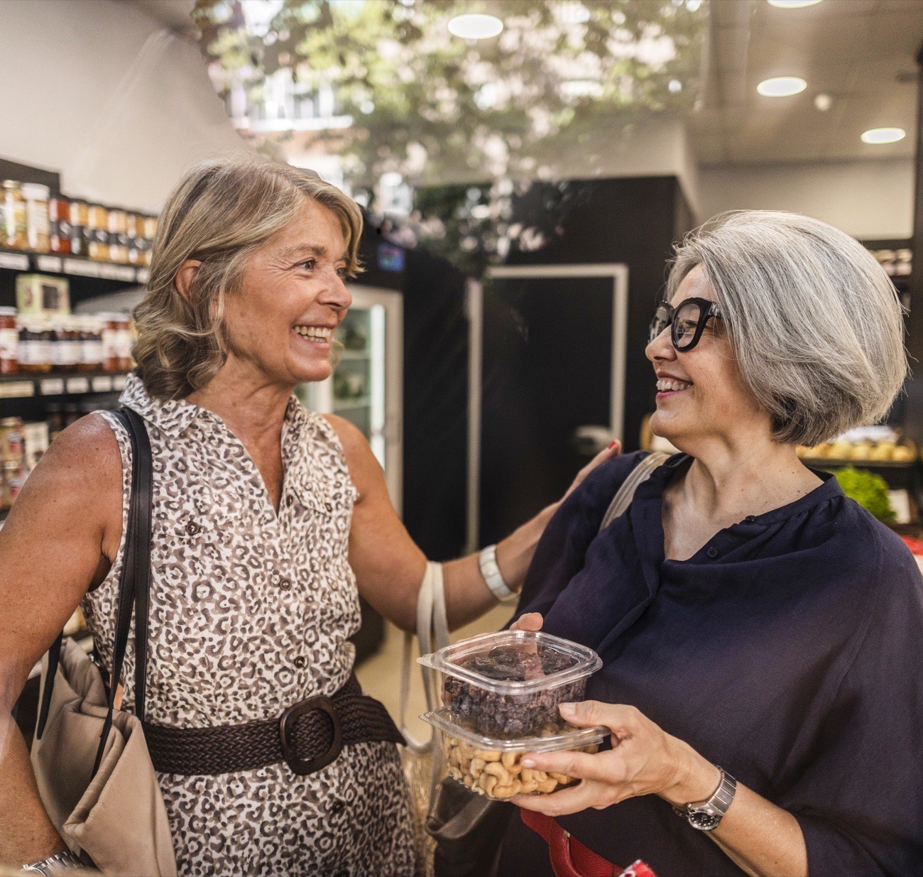 An older woman and her companion choosing groceries together in a shop